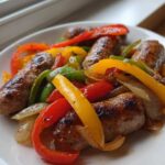 Close-up of browned sausages mixed with colorful bell peppers and onions, a perfect Sheet Pan Sausage and Peppers serving.