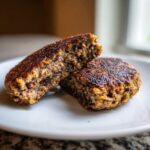 Close-up of a Smoky Black Bean Burger Patty cut in half showing the coarse, dark interior texture.