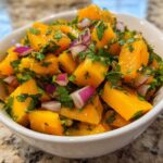 Close-up of vibrant Spicy Mango Salsa featuring diced mango, red onion, and cilantro in a white bowl.