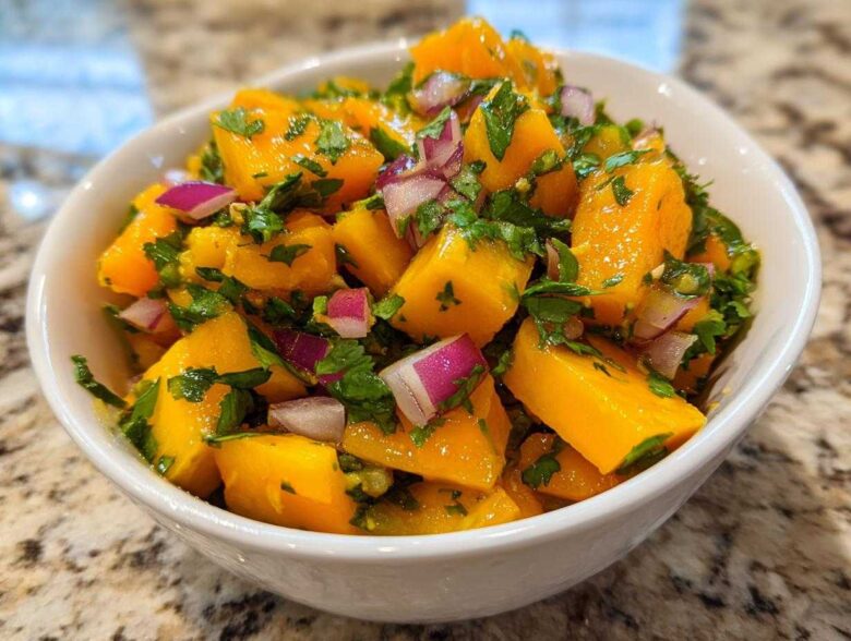 Close-up of vibrant Spicy Mango Salsa featuring diced mango, red onion, and cilantro in a white bowl.