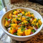 Close-up of vibrant Spicy Mango Salsa featuring diced mango, red onion, and cilantro in a white bowl.
