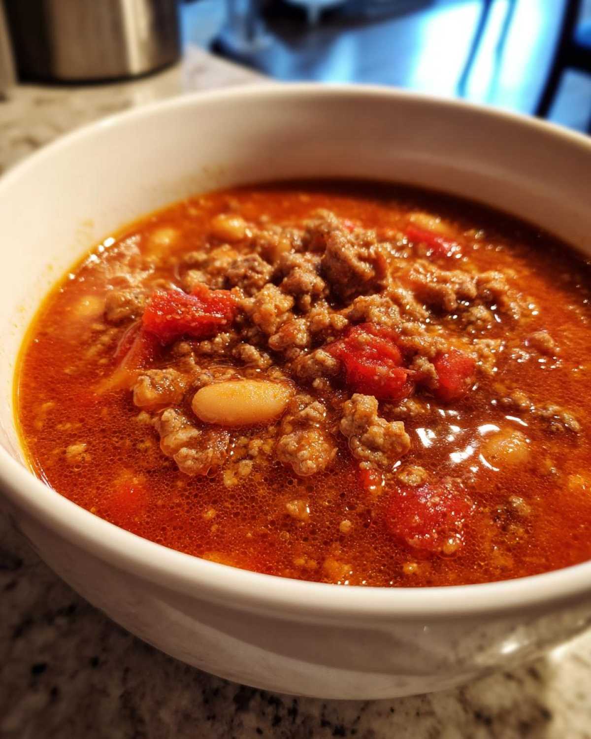 A close-up view of a hearty bowl of Spicy Turkey White Bean Chili, showing ground turkey, white beans, and diced tomatoes in a rich red broth.