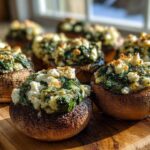 Close-up of baked Spinach and Feta Stuffed Mushrooms with browned tops on a wooden board.