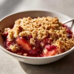 Close-up of a warm serving of Strawberry Rhubarb Crisp showing juicy fruit filling and crumbly topping.