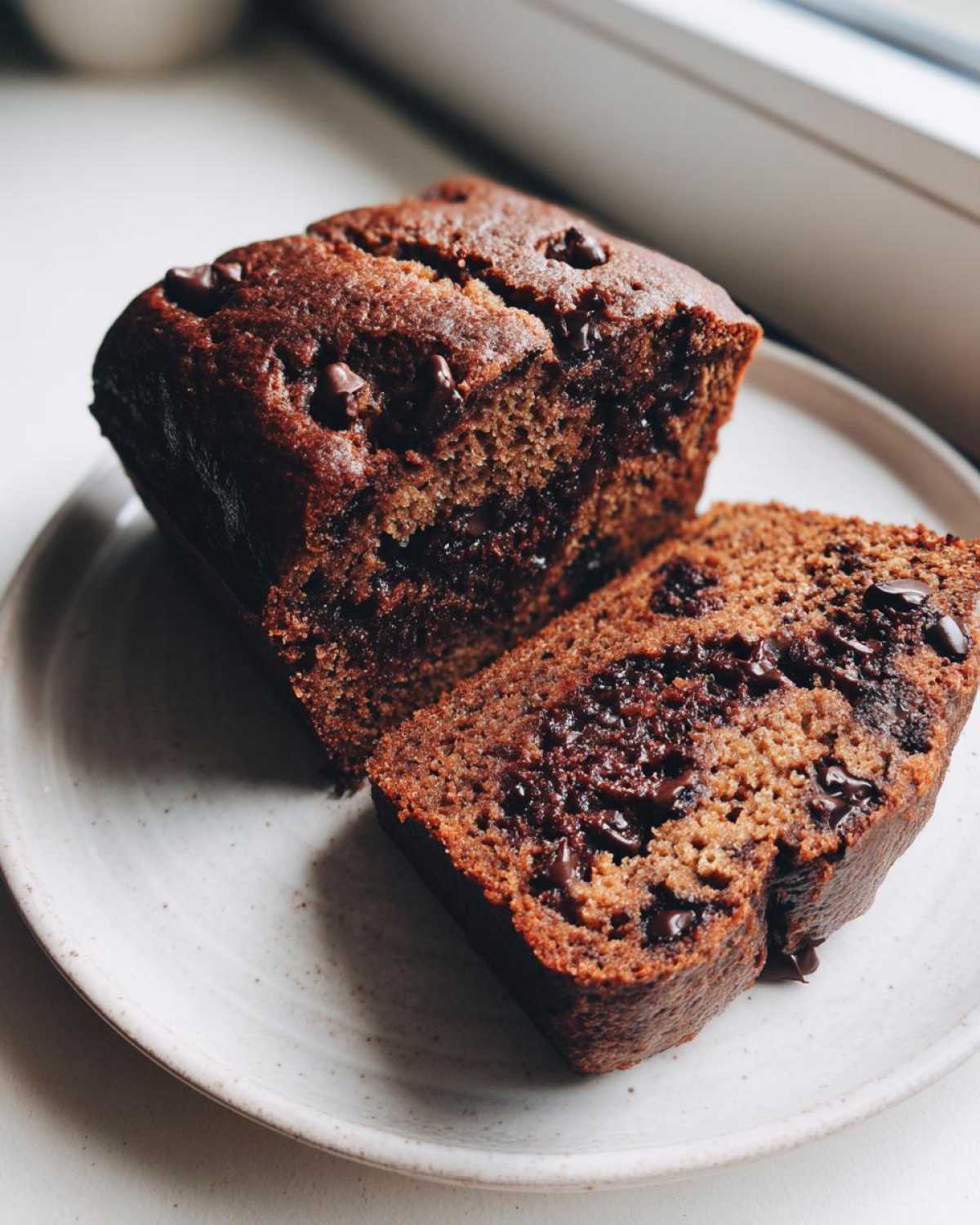 Close-up of a slice cut from Vegan Chocolate Banana Bread, showing moist texture and melted chocolate chips.