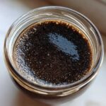 Overhead view of dark, rich Vegan Chocolate Chia Pudding mixture soaking in a glass jar.