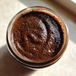 Overhead view of thick, dark Vegan Chocolate Chia Pudding texture in a glass jar.