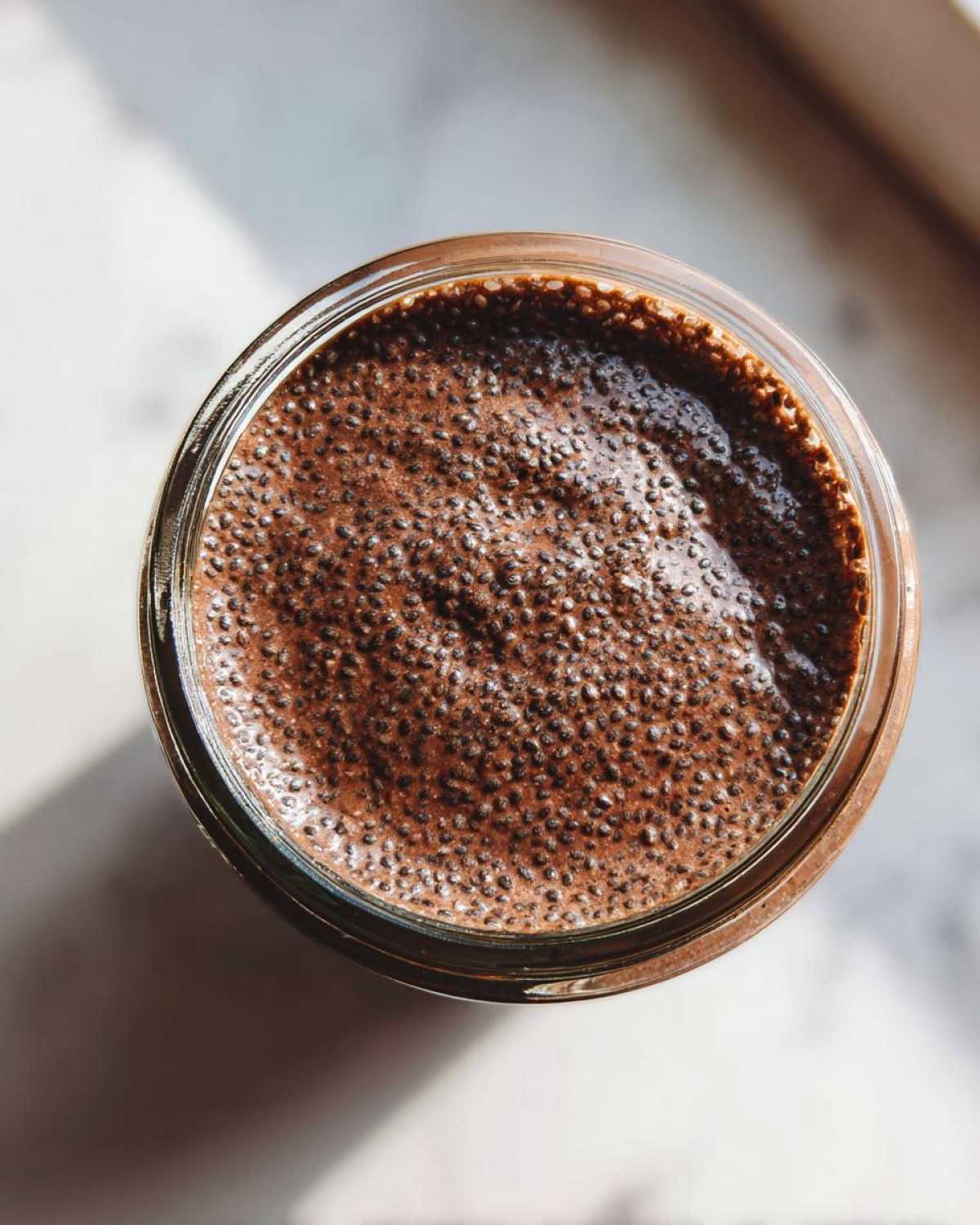 Overhead shot showing the thick, textured surface of Vegan Chocolate Chia Pudding in a glass jar.