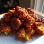 A pile of golden-brown, crispy Air Fryer Crispy BBQ Cauliflower Bites served on a white plate.