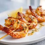 Close-up of perfectly cooked Air Fryer Crispy Cajun Shrimp Skewers garnished with parsley and a lemon wedge.