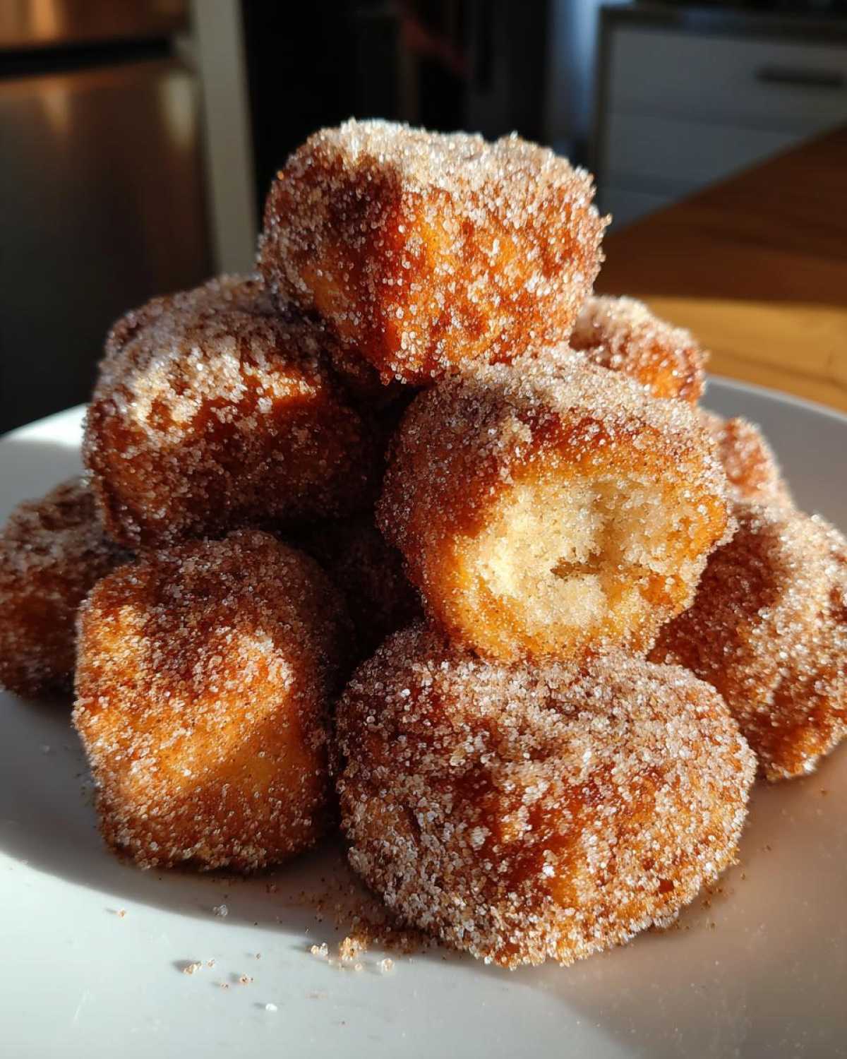 A stack of golden brown Air Fryer Crispy Cinnamon Sugar Biscuit Bites coated heavily in sugar.