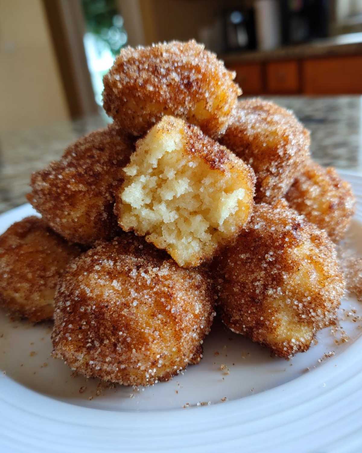 A stack of golden Air Fryer Crispy Cinnamon Sugar Biscuit Bites, one broken open showing the soft interior.