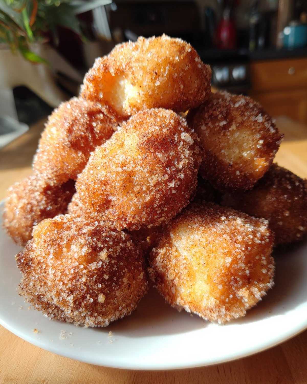 A close-up stack of golden Air Fryer Crispy Cinnamon Sugar Biscuit Bites coated heavily in sparkling cinnamon sugar.