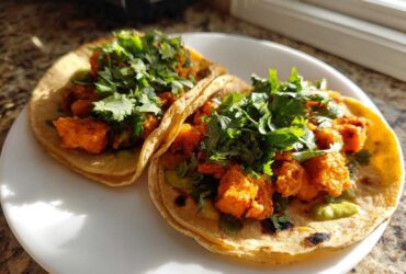 Two warm tortillas filled with orange, seasoned sweet potato chunks and topped generously with fresh cilantro for Air Fryer Crispy Sweet Potato Tacos.