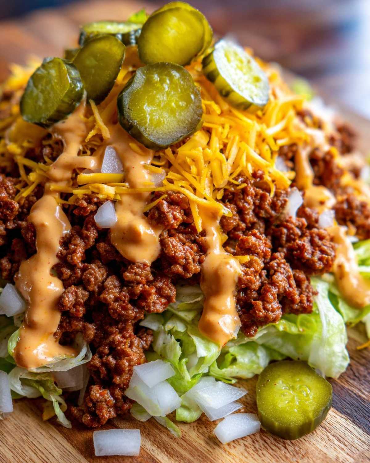 Close-up of a delicious big mac salad featuring seasoned ground beef, shredded cheese, pickles, and special sauce over lettuce.