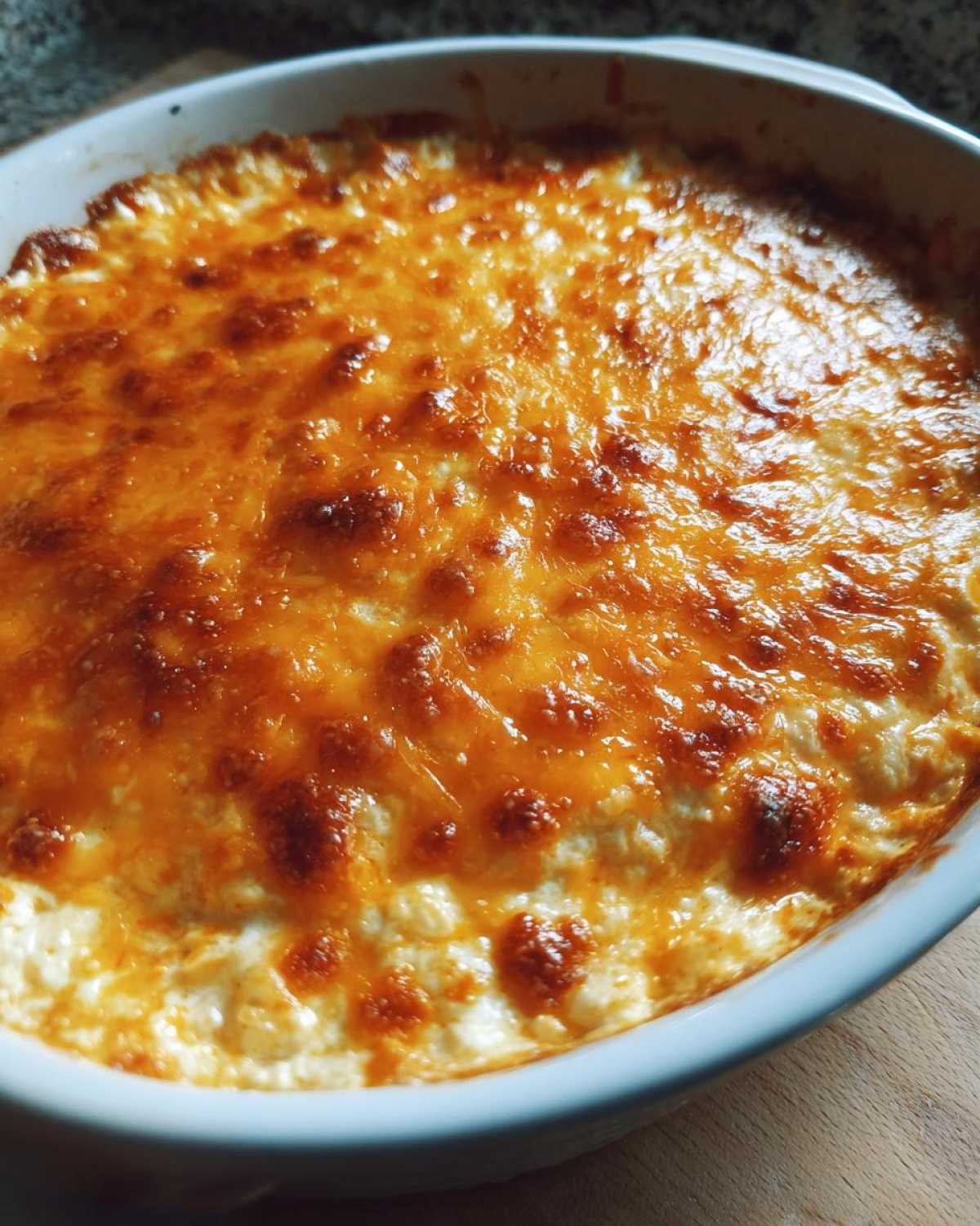 Close-up of baked cottage cheese buffalo chicken dip with a bubbly, golden-brown melted cheese topping.