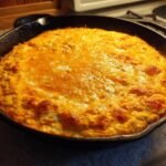 Hot, bubbly cottage cheese buffalo chicken dip topped with melted orange cheese in a black cast iron skillet.