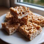 A stack of chewy, golden brown cheerio bars made with puffed cereal and a sweet glaze, ready to eat.