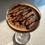 Close-up overhead view of a creamy chocolate martini garnished with a dark chocolate drizzle.