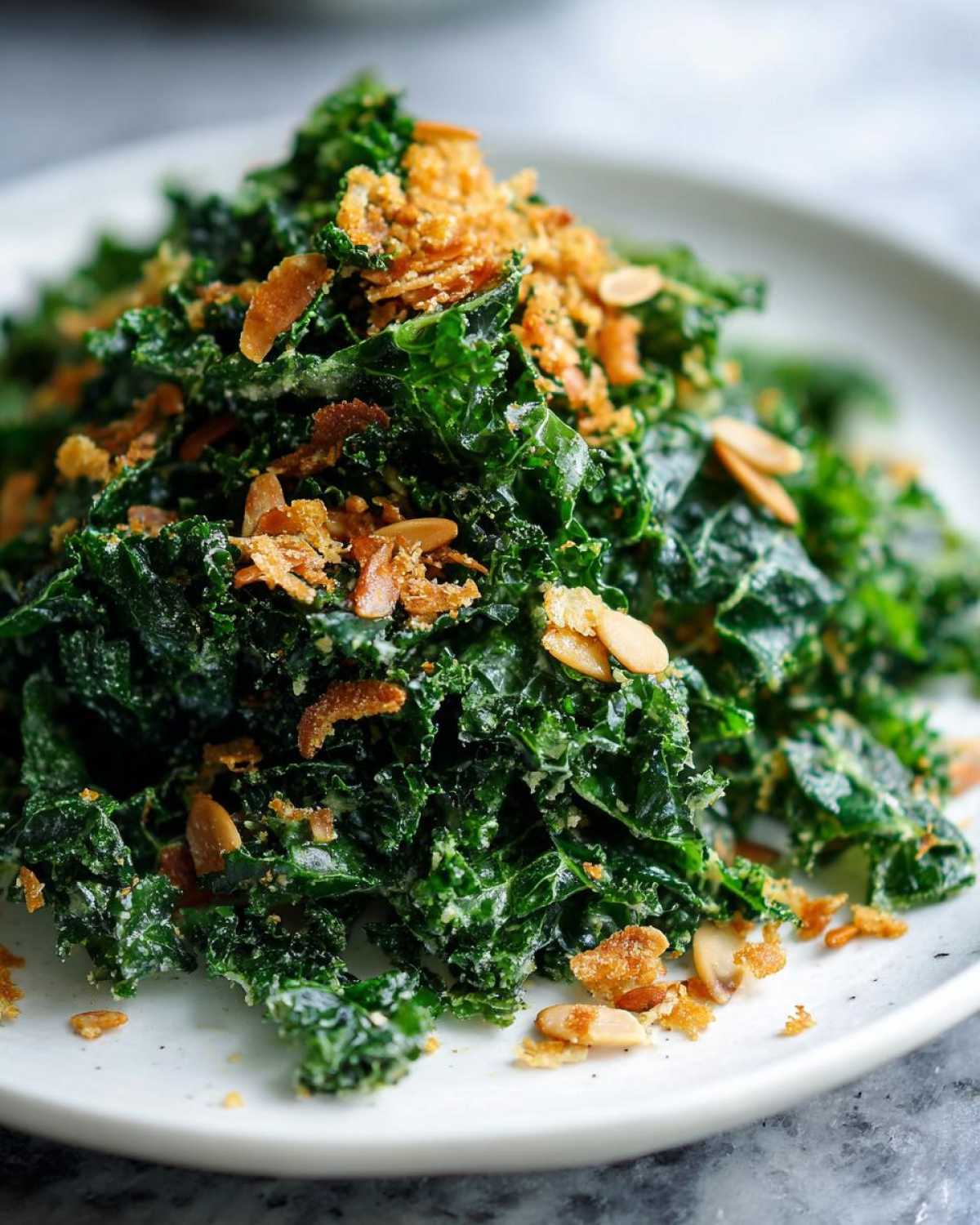 A close-up of Copycat Kale Crunch Salad tossed in dressing and topped with crunchy breadcrumbs and sliced almonds.