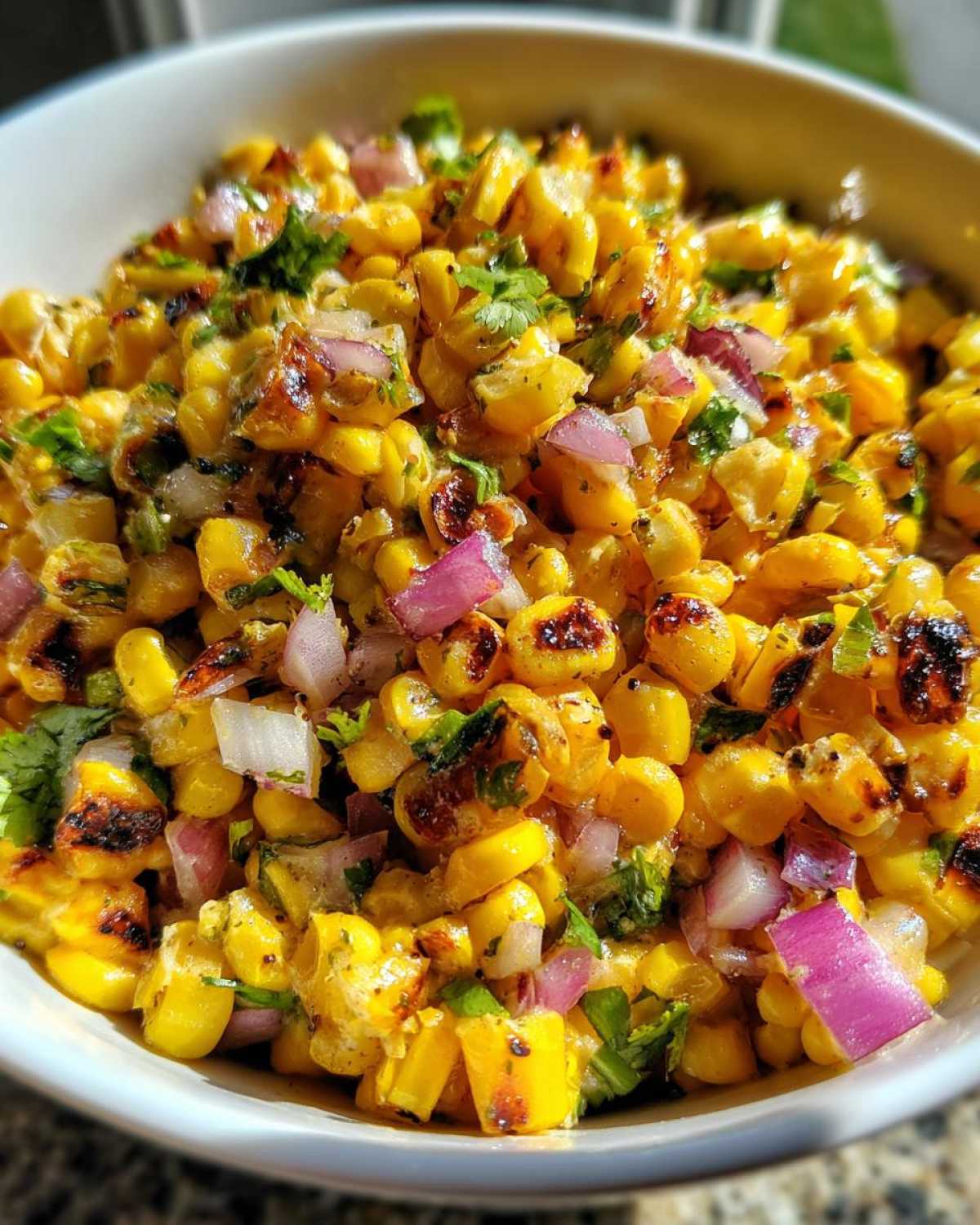 Close-up of vibrant Copycat Mexican Grill Corn Salsa featuring charred corn kernels, diced red onion, and cilantro.