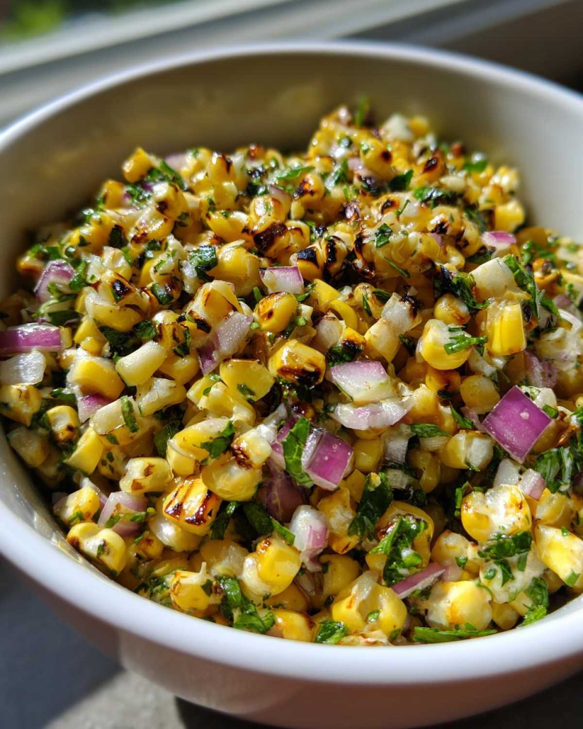 Close-up of vibrant Copycat Mexican Grill Corn Salsa featuring charred corn kernels, diced red onion, and fresh cilantro.
