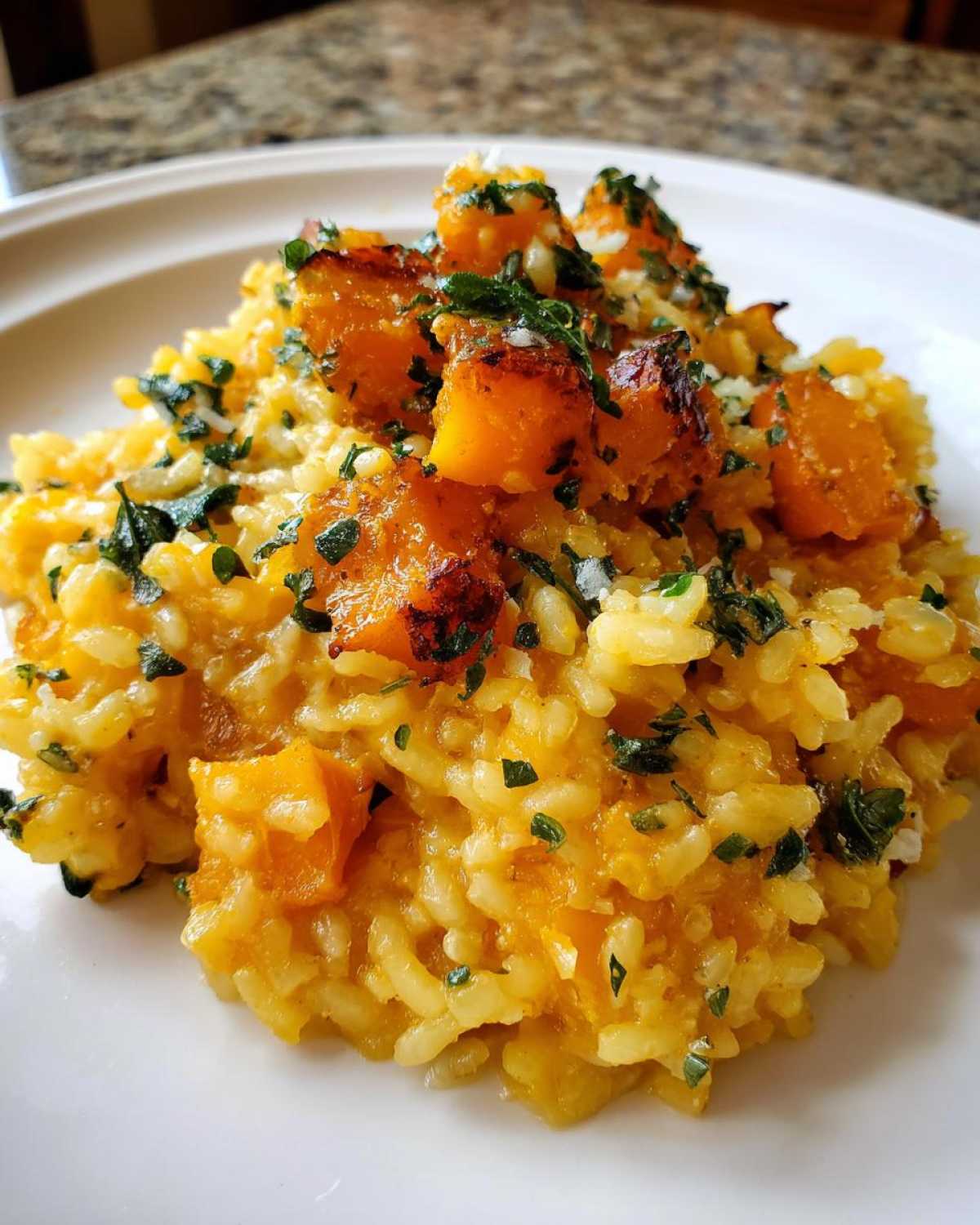 Close-up of creamy butternut squash risotto topped with roasted squash cubes and fresh parsley.