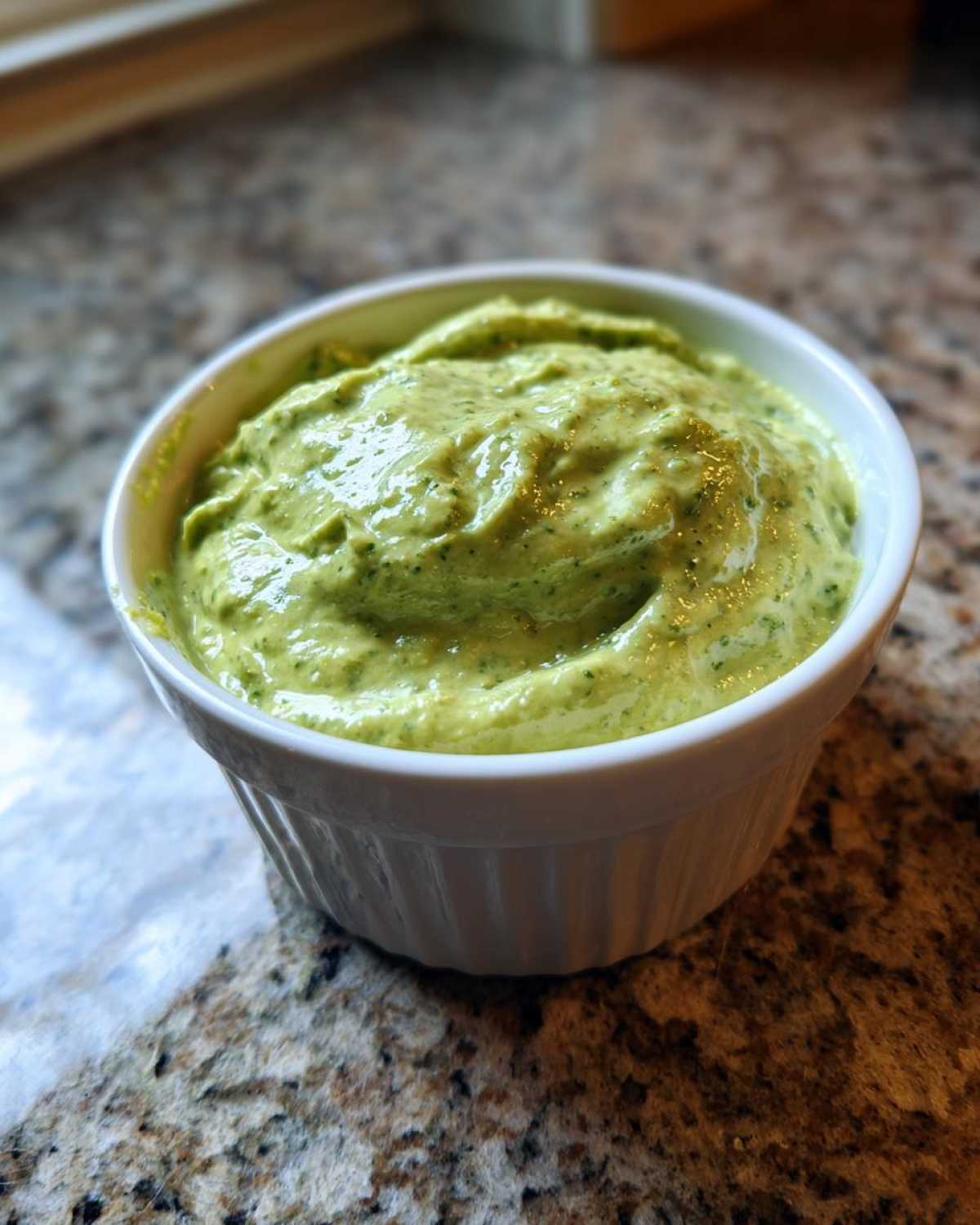 Close-up of thick, vibrant green Easy 5-Minute Salsa Verde Yogurt Dip served in a small white fluted ramekin.