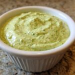 Close-up of creamy, light green Easy 5-Minute Salsa Verde Yogurt Dip served in a small white ramekin.