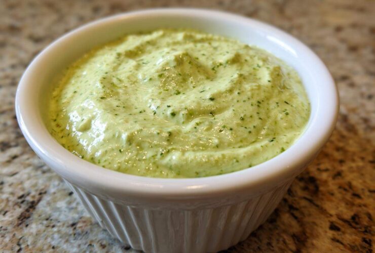 Close-up of creamy, light green Easy 5-Minute Salsa Verde Yogurt Dip served in a small white ramekin.