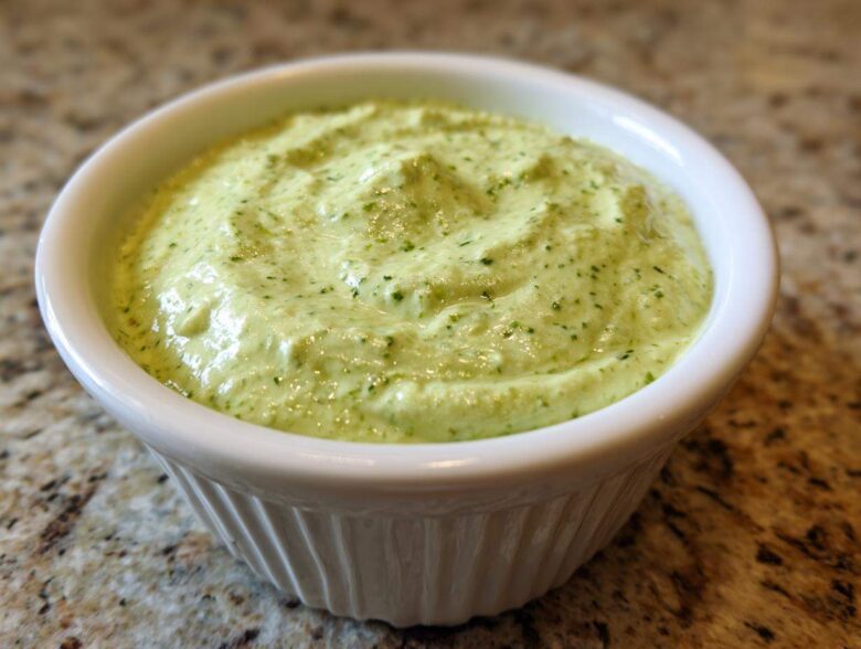Close-up of creamy, light green Easy 5-Minute Salsa Verde Yogurt Dip served in a small white ramekin.