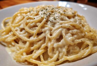 Close-up of spaghetti generously coated in creamy Easy Cottage Cheese Alfredo Sauce and sprinkled with herbs.