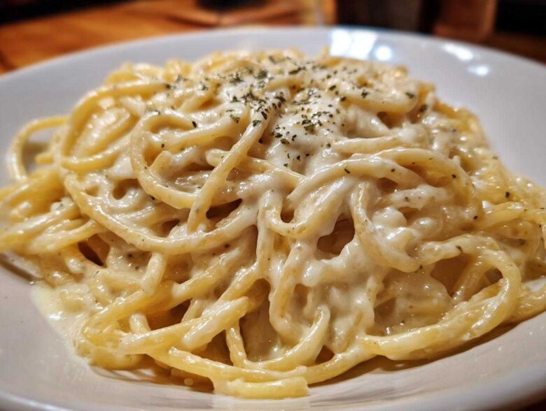 Close-up of spaghetti generously coated in creamy Easy Cottage Cheese Alfredo Sauce and sprinkled with herbs.