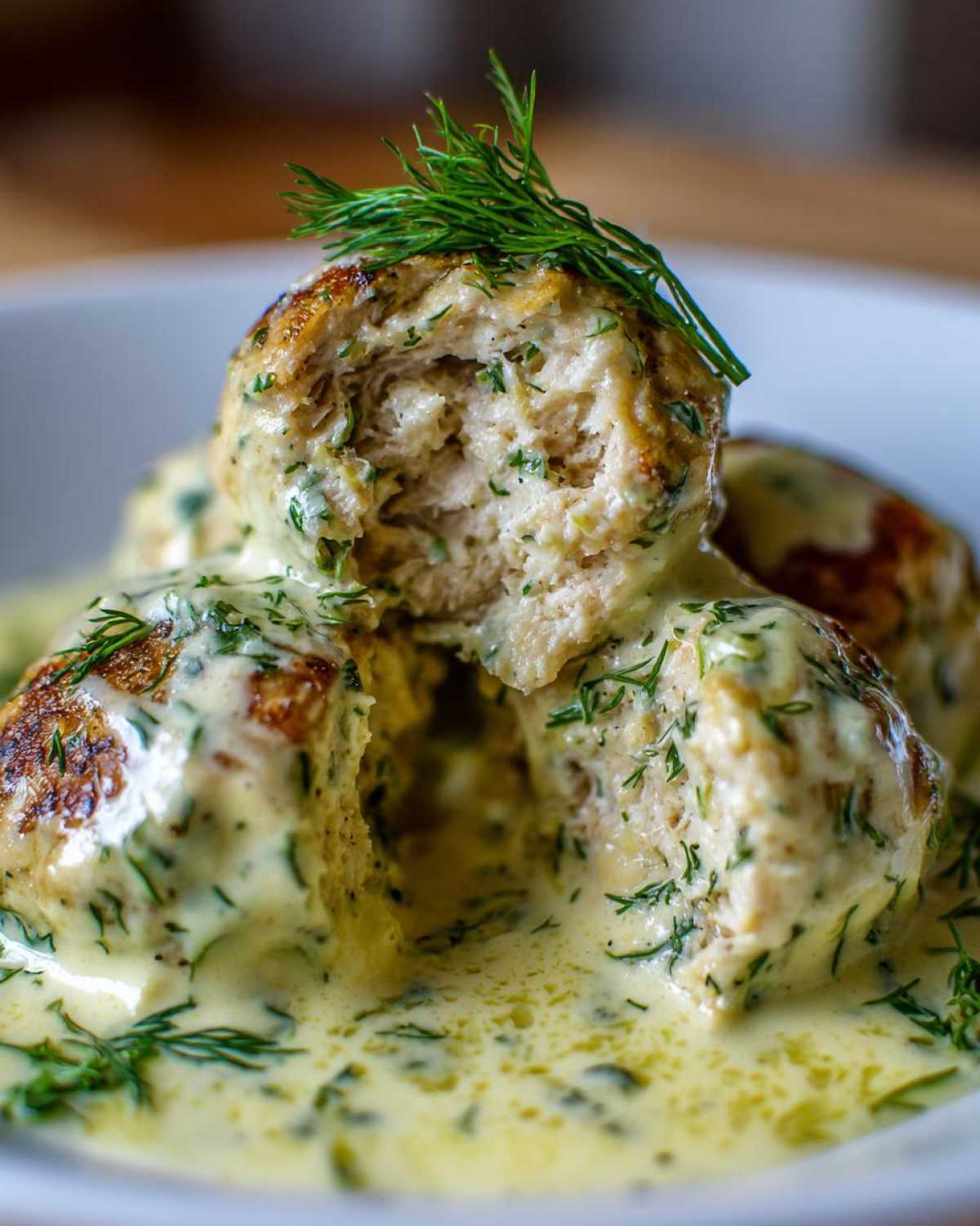 Close-up of Easy Creamy Greek Chicken Meatballs cut open, smothered in a creamy dill sauce.