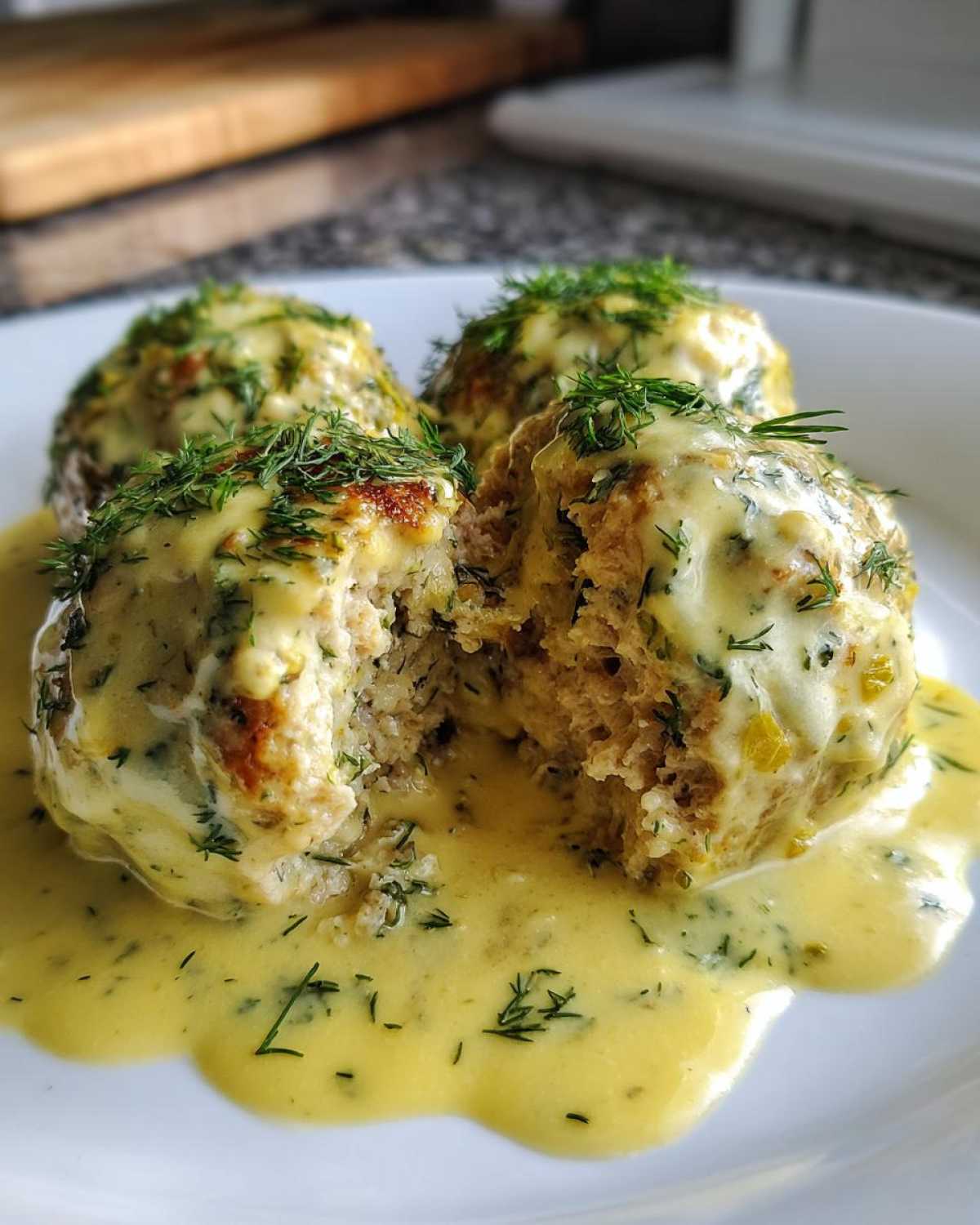 Close-up of Easy Creamy Greek Chicken Meatballs covered in a yellow sauce and fresh dill.