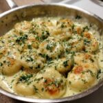 Close-up of Easy One-Pan Creamy Garlic Butter Gnocchi simmering in a stainless steel skillet, topped with fresh parsley.
