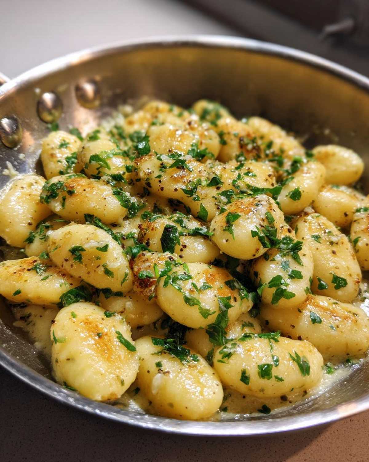 Close-up of pan-seared gnocchi coated in a creamy garlic butter sauce and fresh parsley, ready to serve.