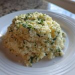 A mound of fluffy Easy One-Pot Creamy Lemon Herb Couscous topped with fresh chopped parsley.