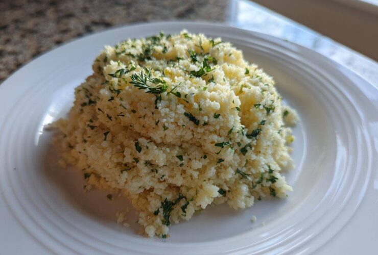 A mound of fluffy Easy One-Pot Creamy Lemon Herb Couscous topped with fresh chopped parsley.