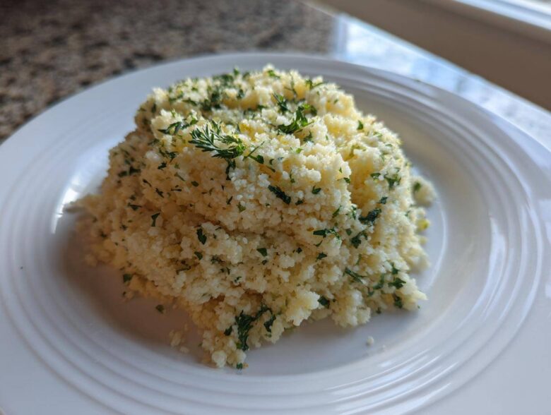 A mound of fluffy Easy One-Pot Creamy Lemon Herb Couscous topped with fresh chopped parsley.