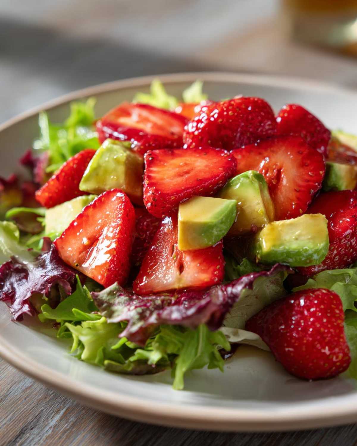 Close-up of a vibrant Easy Strawberry Avocado Salad featuring sliced strawberries and avocado chunks over mixed greens.
