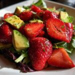 Close-up of a vibrant Easy Strawberry Avocado Salad featuring sliced strawberries, avocado chunks, and mixed greens lightly coated in vinaigrette.