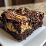 A close-up view of a thick, fudgy peanut butter swirl brownies square served on a white plate.