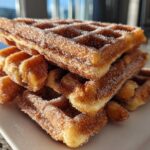 A close-up stack of crispy Gluten-Free Cinnamon Sugar Waffle Sticks heavily coated in sparkling cinnamon sugar.