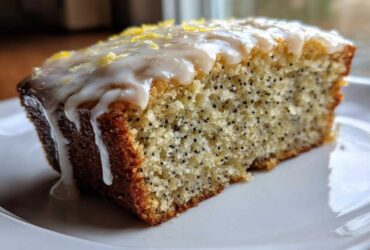 Close-up of a moist slice of Gluten-Free Lemon Almond Poppy Seed Cake with thick lemon glaze and zest.
