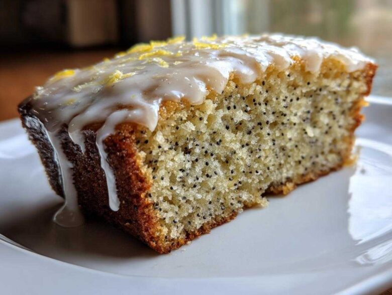 Close-up of a moist slice of Gluten-Free Lemon Almond Poppy Seed Cake with thick lemon glaze and zest.
