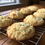 Close-up of several Gluten-Free Lemon Thyme Shortbread Cookies cooling on a wire rack near a window.