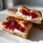 Two halves of a flaky pastry filled with cream cheese and strawberry jam, showcasing the layers of a Gluten-Free Strawberry Cream Cheese Danishes.