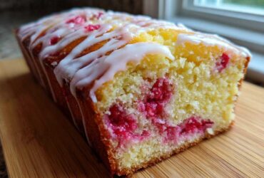 Close-up of a Gluten-Free Strawberry Lemon Pound Cake loaf with visible berries and white lemon glaze drizzle.