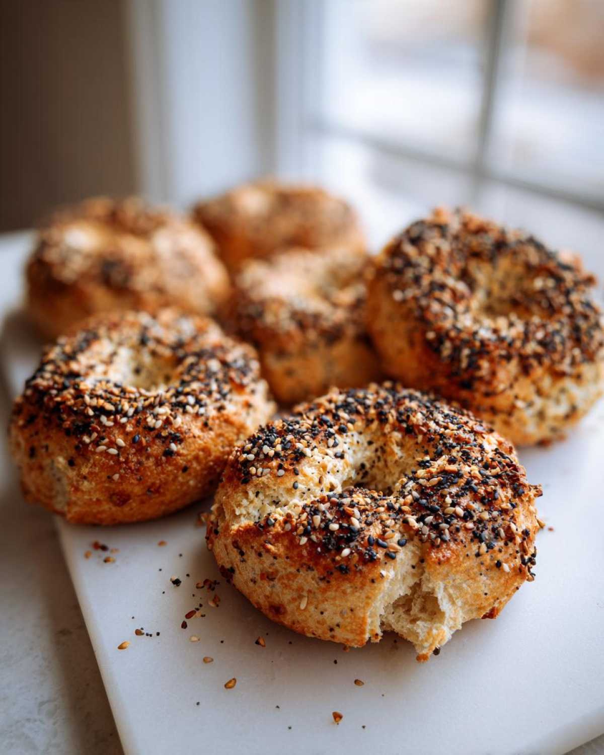 Close-up of several High-Protein Cottage Cheese Bagel Bites topped with everything bagel seasoning on a white surface.